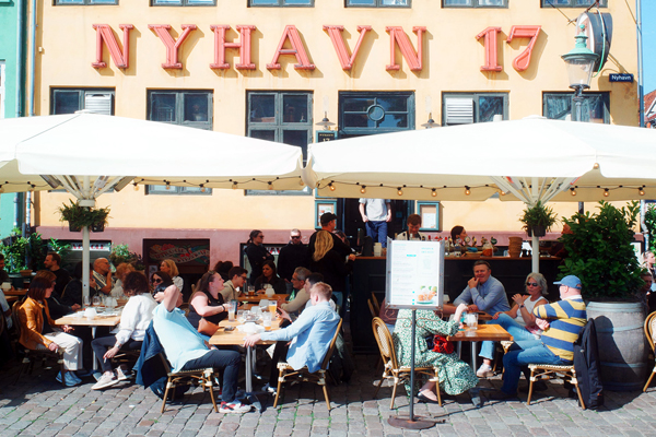 Gente ai tavoli del ristorante Nyhavn 17 al porto antico